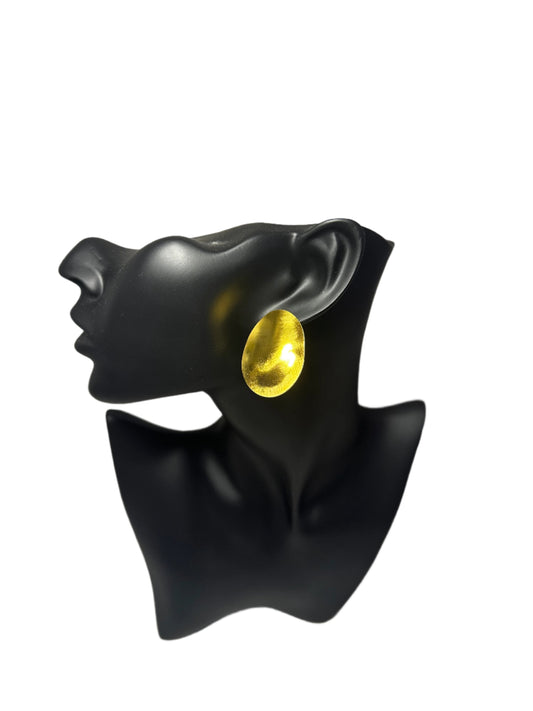 a gold earring displayed on a black mannequin head , showcasing its elegant design and shine against a white background