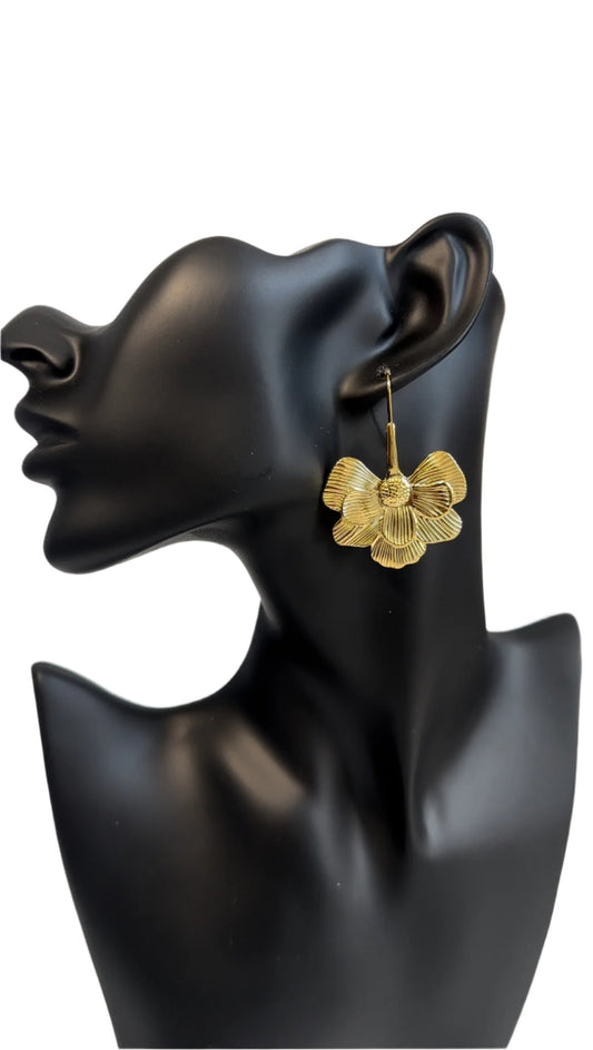 A delicate gold earring featuring a beautifully crafted flower design, showcasing elegance and charm on a black mannequin.