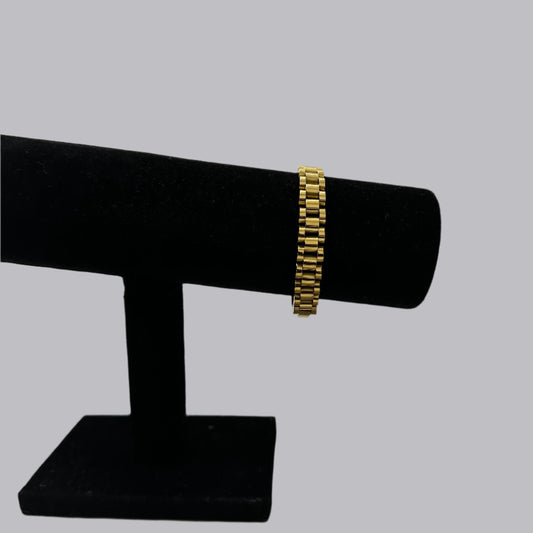 a black jewelry stand holds thick gold link bracelet with a soft light gray background